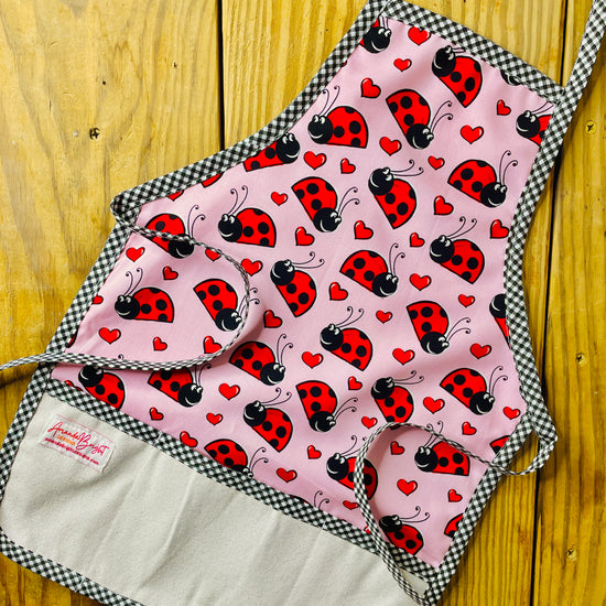 Amanda Bright Designs Children's ladybug apron pink with red and black ladybugs and black checkered trim