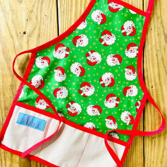 Two Medium Sized Ladies Winking Santas Vintage Style Children's Christmas Aprons green with gold starbursts and red aprons strings