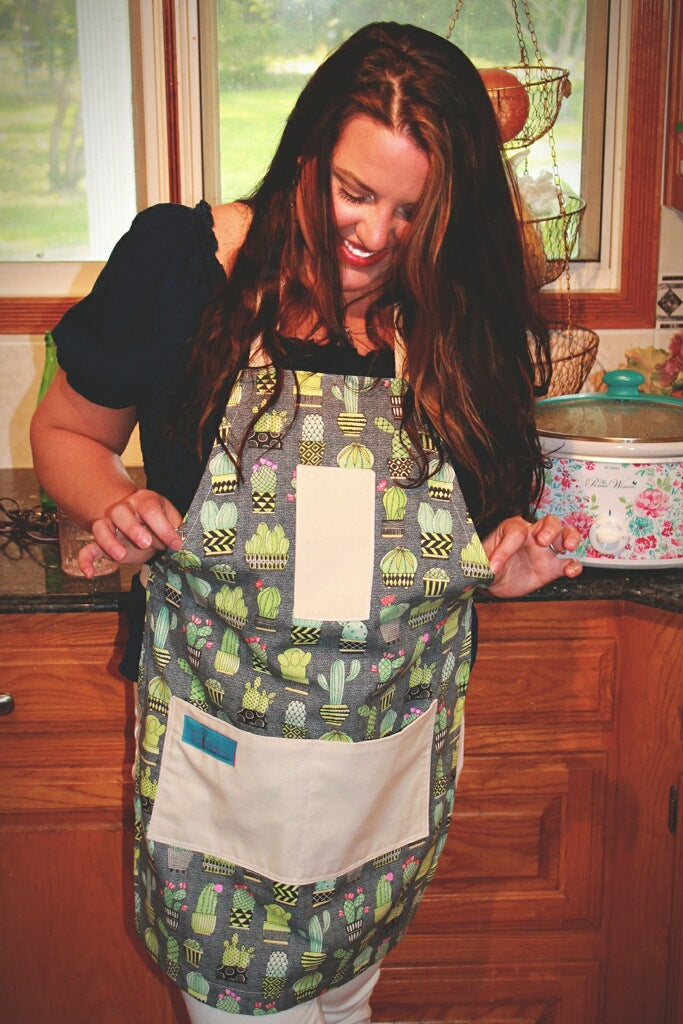 Two Medium Sized Ladies cactus kitchen apron lifestyle working in kitchen holding out sides Chloe
