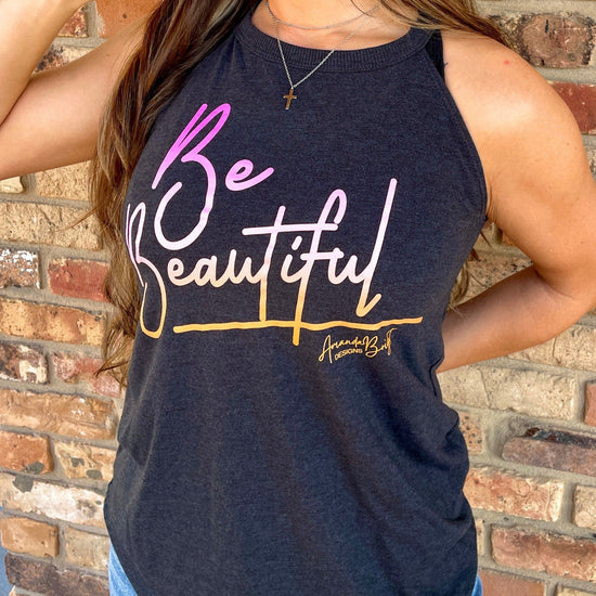 Amanda Bright Designs female model wearing a dark gray tank top with the text 'BE BEAUTIFUL' and a signature tagline printed in sunset colors.