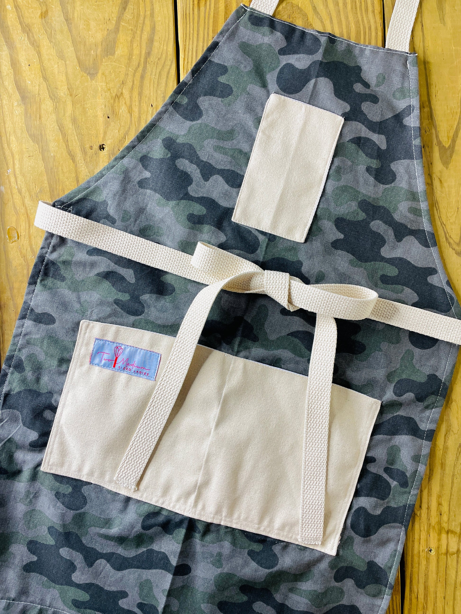 Amanda Bright Designs camouflage apron featuring gray and green color scheme, with canvas pockets and an adjustable straps