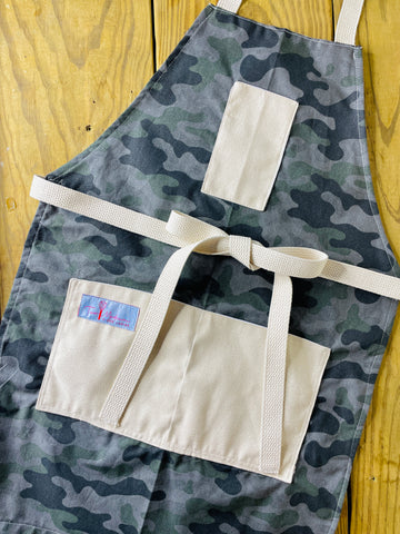 Amanda Bright Designs camouflage apron featuring gray and green color scheme, with canvas pockets and an adjustable straps
