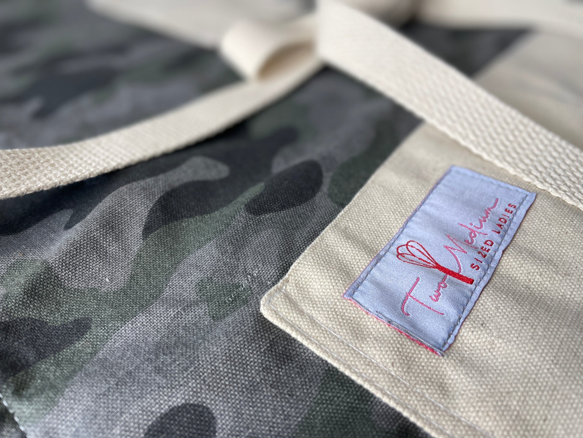 Amanda Bright Designs camouflage apron featuring gray and green color scheme, with canvas pockets and an adjustable straps
