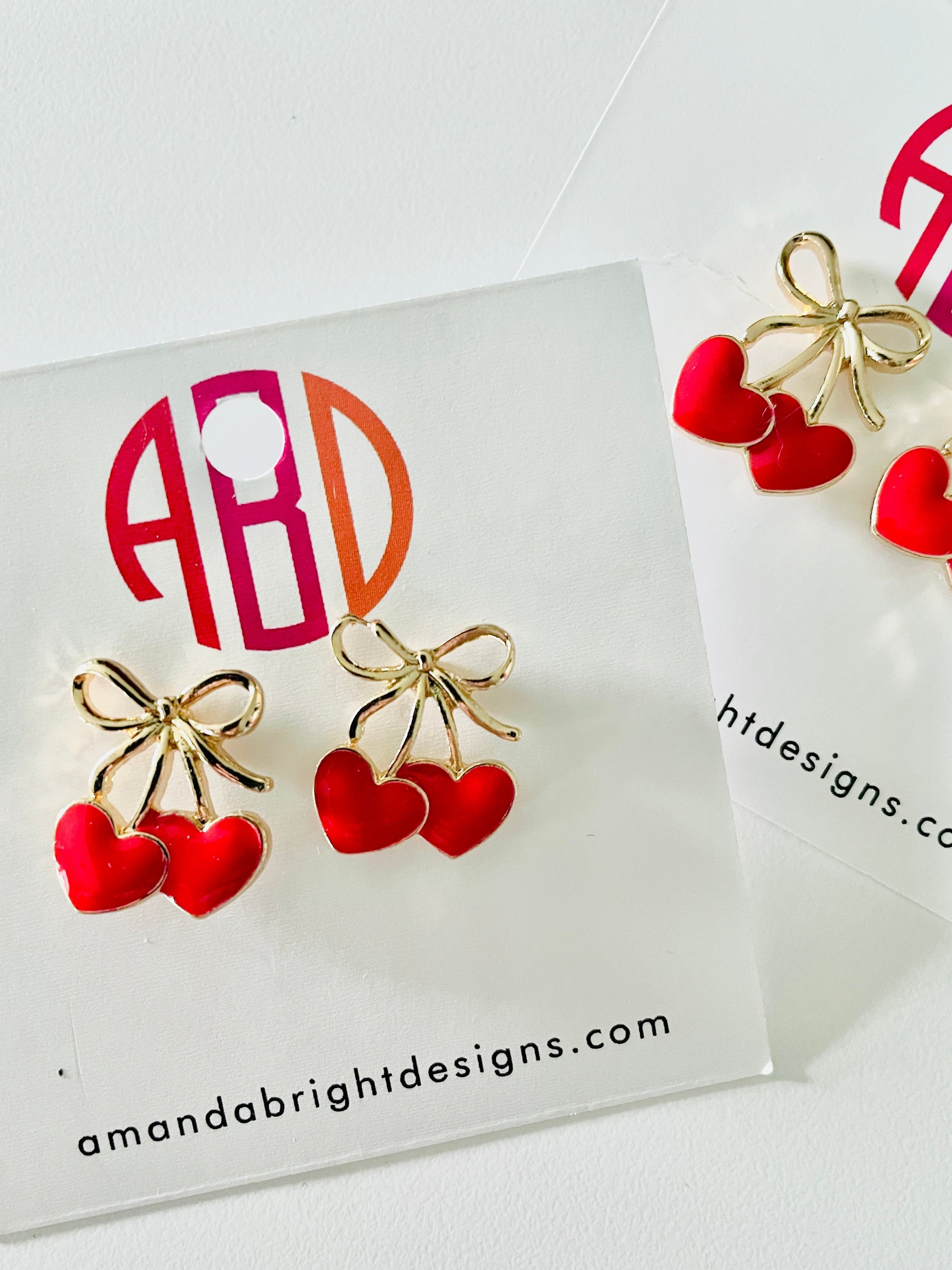 Amanda Bright Designs pair of gold bow and red heart stud earrings