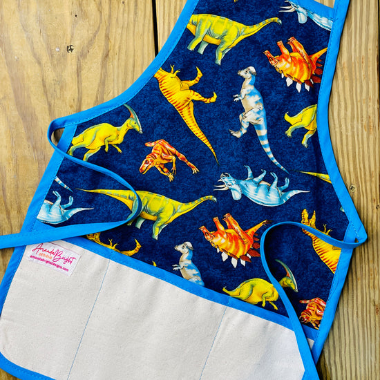Amanda Bright Designs childrens dinosaurs apron stegosaurus tyrannosaurus triceratops extinct species for bake time play time blue apron strings