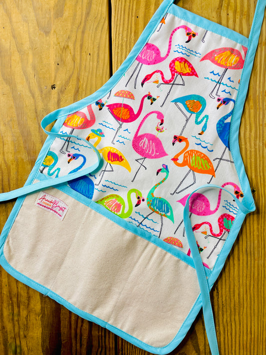 Amanda Bright Designs children’s kitchen apron with a colorful flamingo print on a white background, featuring Tiffany blue trim and natural canvas front pockets