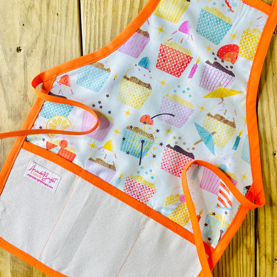 Amanda bright designs children’s birthday party apron featuring colorful cupcakes with frosting decorations fruit for birthday celebrations