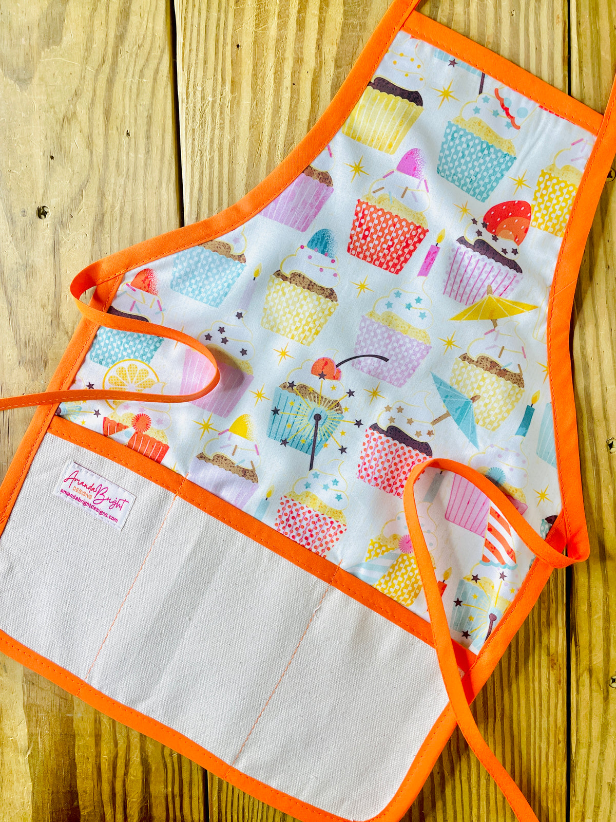 Amanda bright designs children’s birthday party apron featuring colorful cupcakes with frosting decorations fruit for birthday celebrations