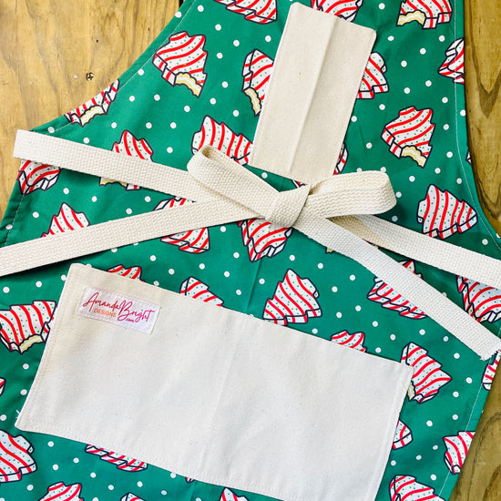 Amanda Bright Designs Couture Apron Little Debbie white with red icing Christmas Tree Cake Apron on green polkadot fabric for the holidays