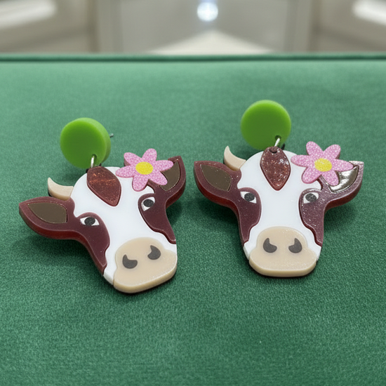 Amanda Bright Designs brown and white cow-shaped earrings with pink flower and green acrylic stud earrings