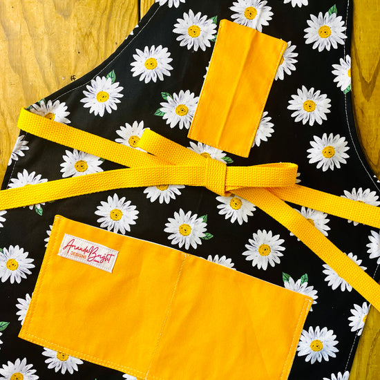 Amanda Bright Designs black apron with white daisy pattern apron with gold strings and pockets