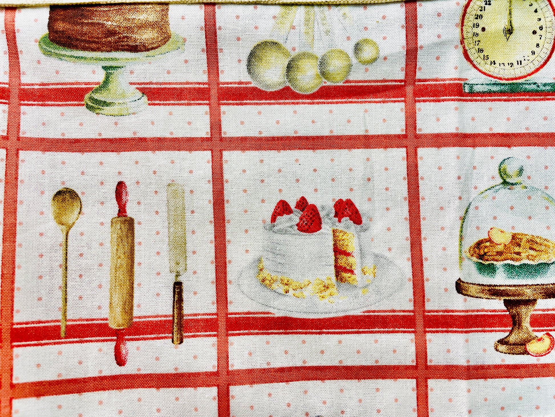 Amanda Bright Designs white baking apron with a red checkered pattern featuring illustrations of baking-related items like a cake, pie, and rolling pin domed cupcakes with canvas pockets and cotton strings