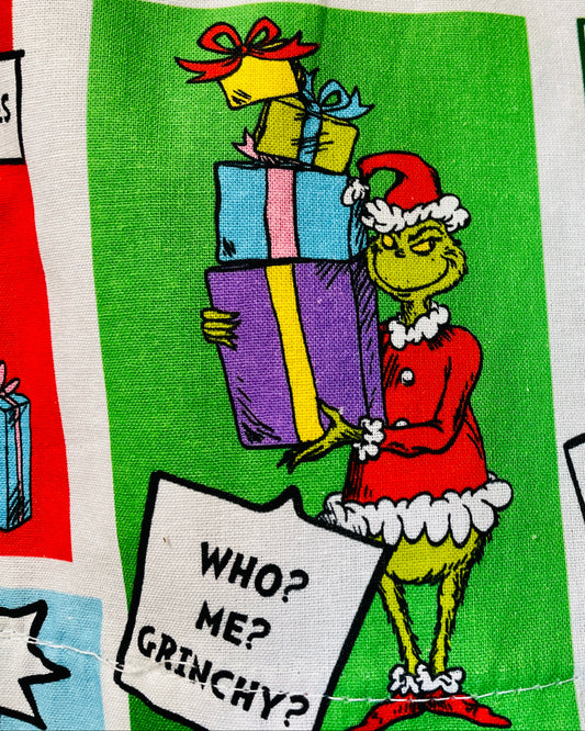 closeup of Fabric with Grinch Christmas-themed design featuring colorful presents and text.