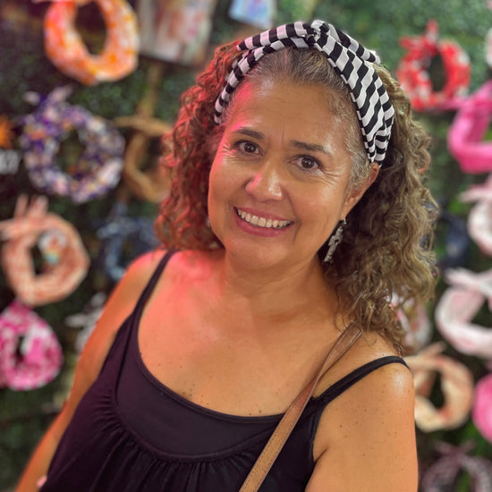 A smiling woman with curly brown hair wearing a black and white striped headband halloween