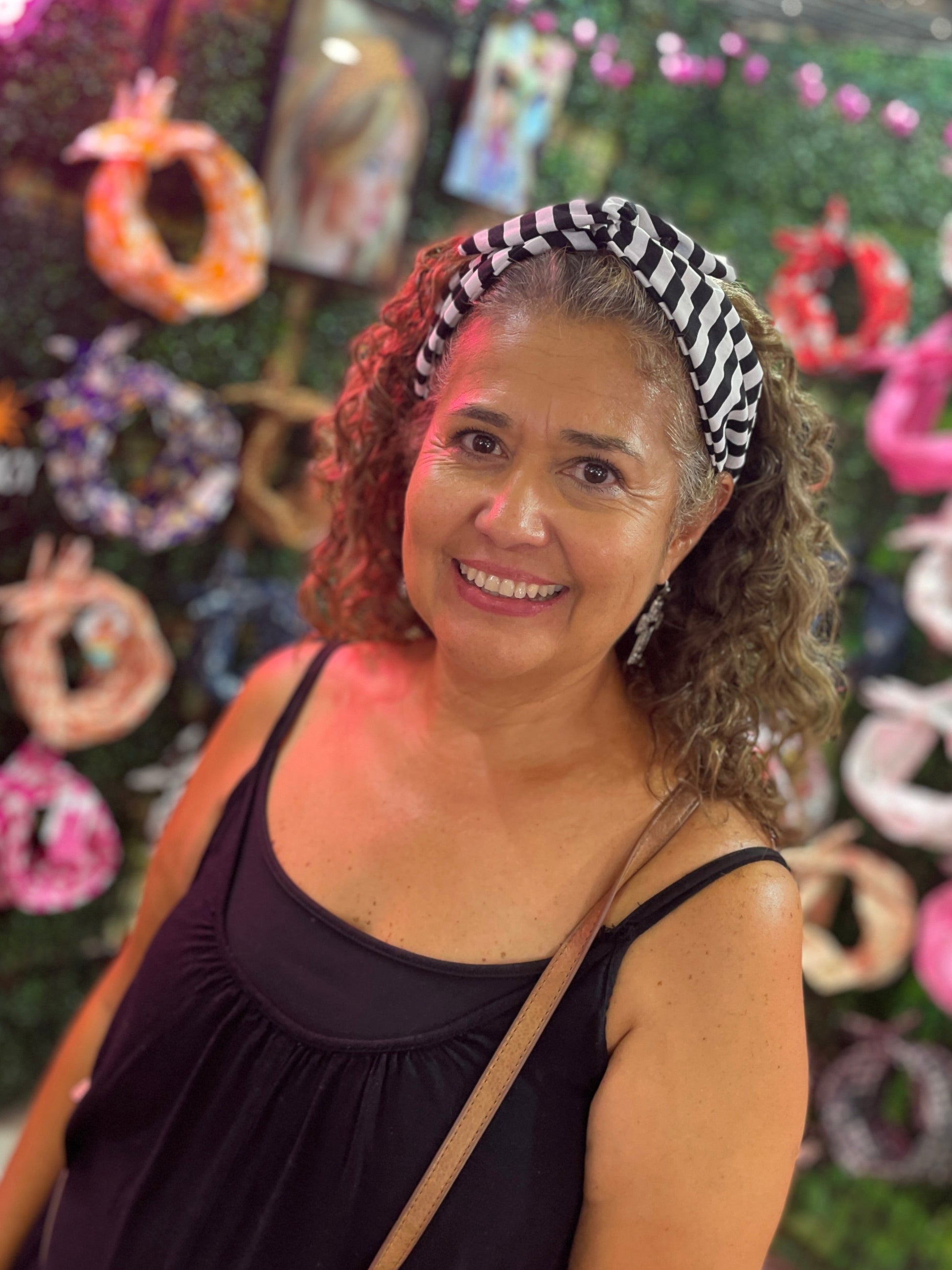 A smiling woman with curly brown hair wearing a black and white striped headband halloween