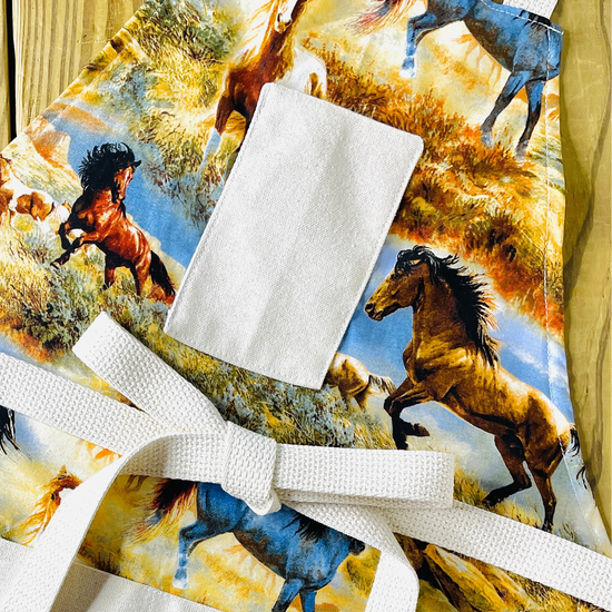 Amanda Bright Designs hadleigh mustang apron colorful print of running horses in a grassy landscape