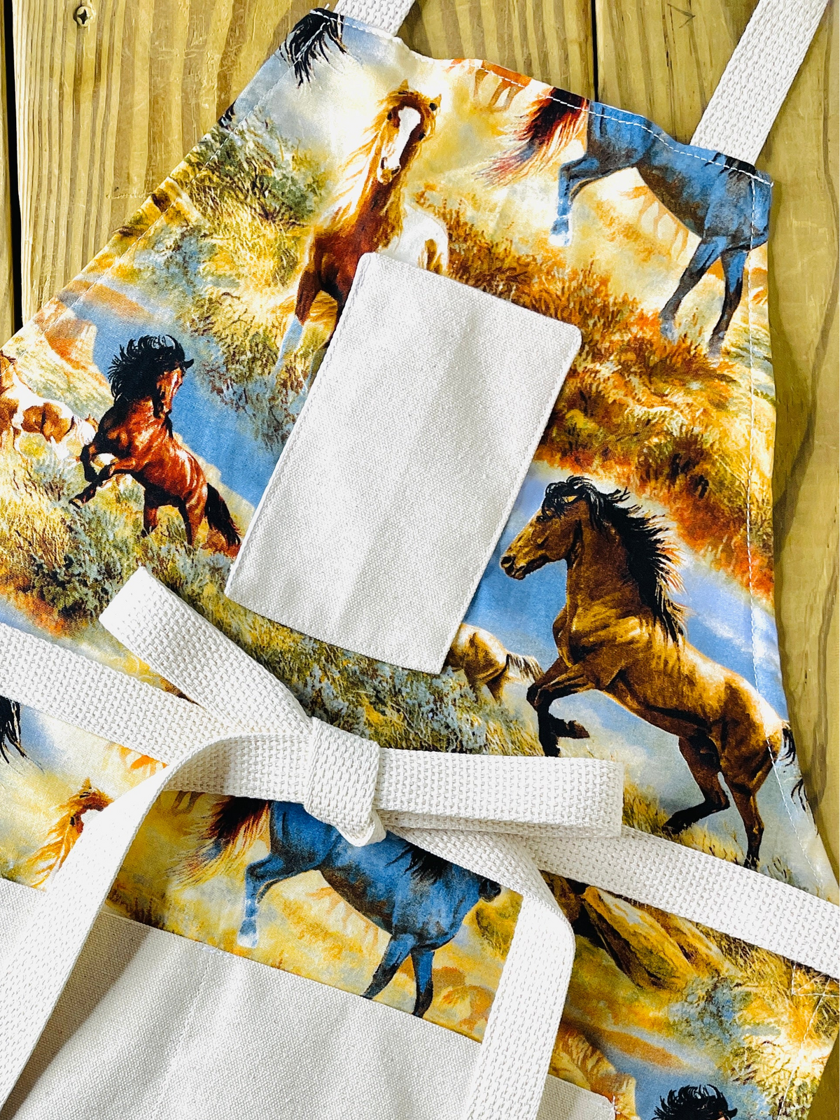 Amanda Bright Designs hadleigh mustang apron colorful print of running horses in a grassy landscape