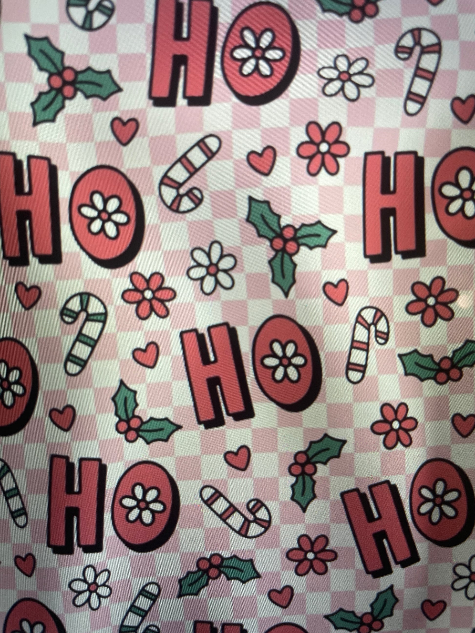 Patterned fabric with 'HO HO HO' text, candy canes, flowers, and holly leaves on a checkered background Amanda Bright Designs Couture Apron