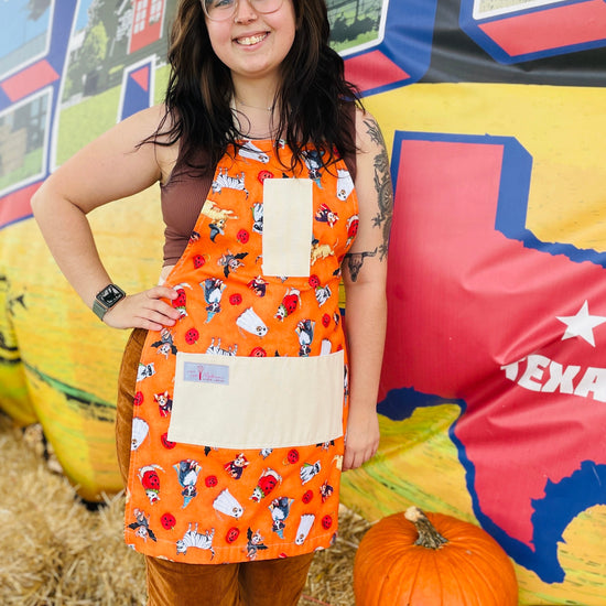 Amanda Bright Designs halloween apron model featuring dogs in costumes on orange backgroun