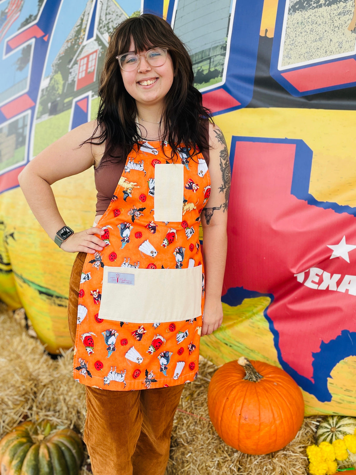 Amanda Bright Designs halloween apron model featuring dogs in costumes on orange backgroun