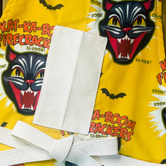 Amanda Bright Designs Ka-Boom Black Cat Fireworks Yellow and Black Bats Halloween theme Apron