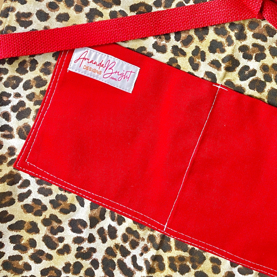 Kat Retro Designer Midcentury Apron Leopard 1950s Glamorous Animal Print Red Strings and Pockets on model