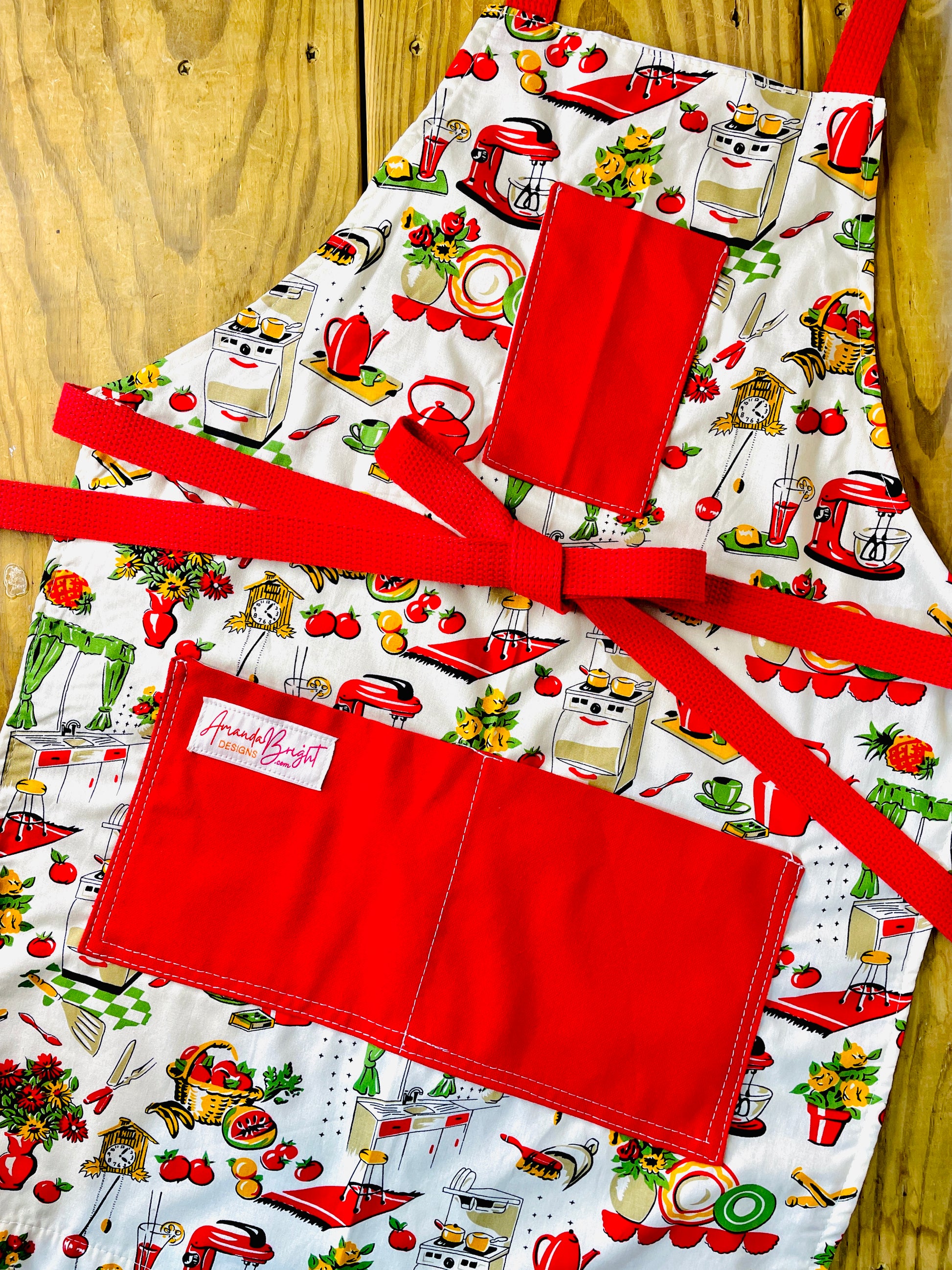 Amanda Bright Designs Lucille apron 1950s kitchen appliances pattern in red and green with red pockets and strings 