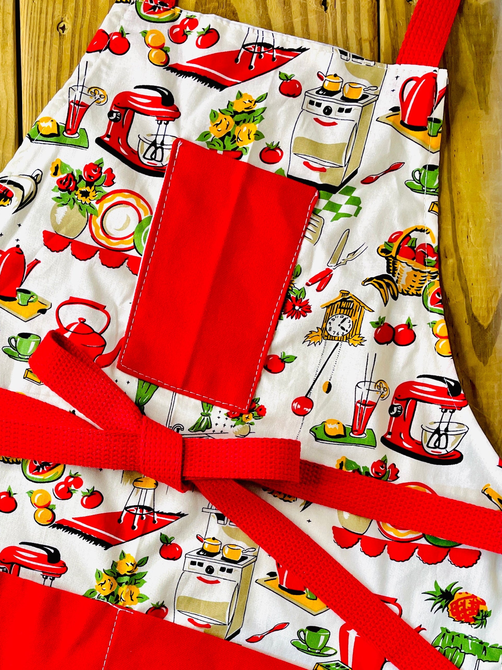 Amanda Bright Designs Lucille apron 1950s kitchen appliances pattern in red and green with red pockets and strings 