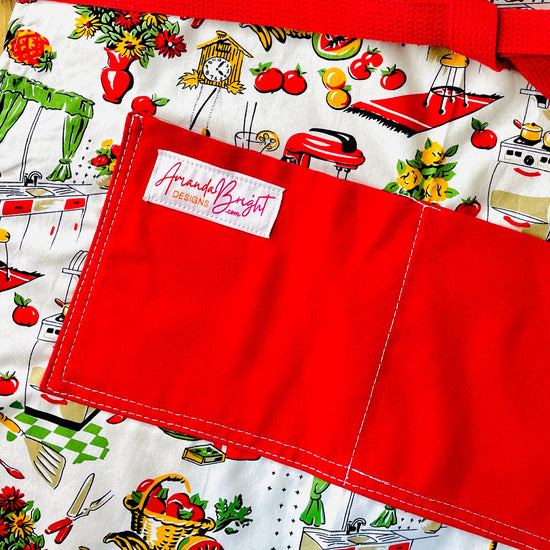 Amanda Bright Designs Lucille apron 1950s kitchen appliances pattern in red and green with red pockets and strings 