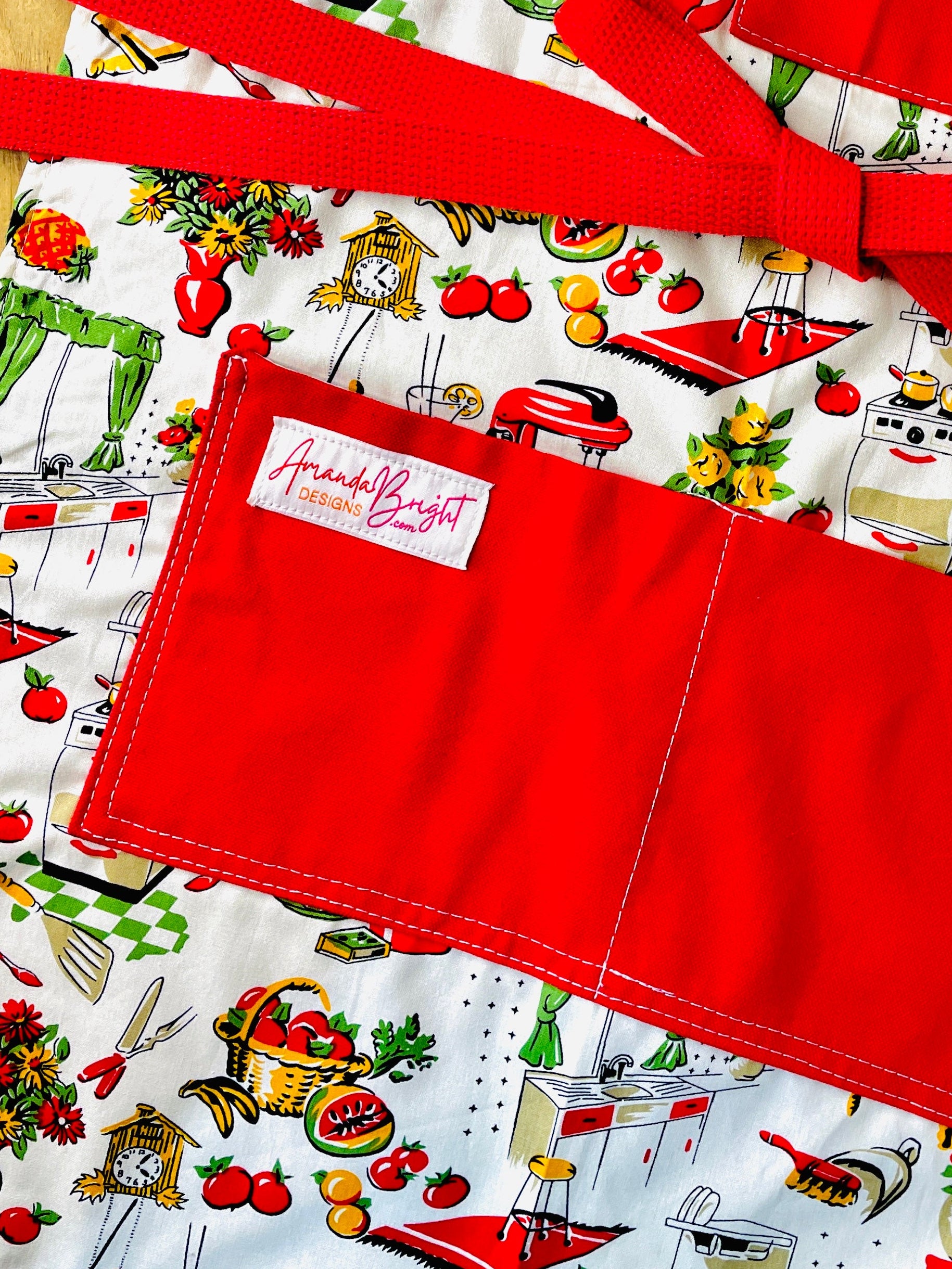 Amanda Bright Designs Lucille apron 1950s kitchen appliances pattern in red and green with red pockets and strings 