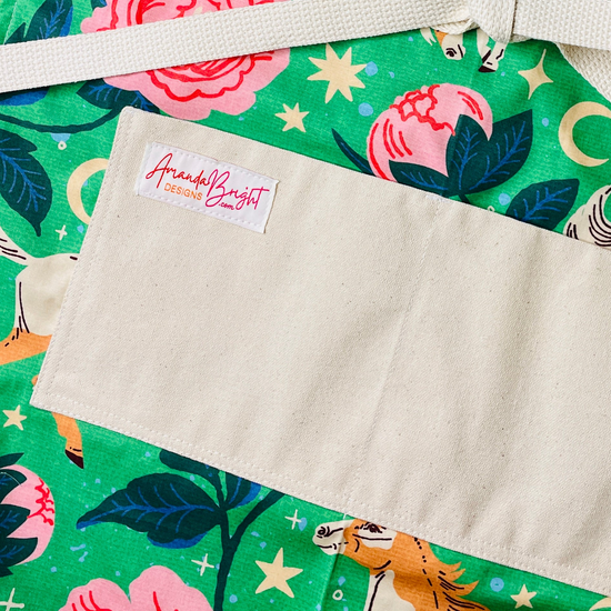 moonlit meadows pockets apron Galloping pintos, blooming peonies, and celestial moons and stars come together on a vibrant emerald green background 