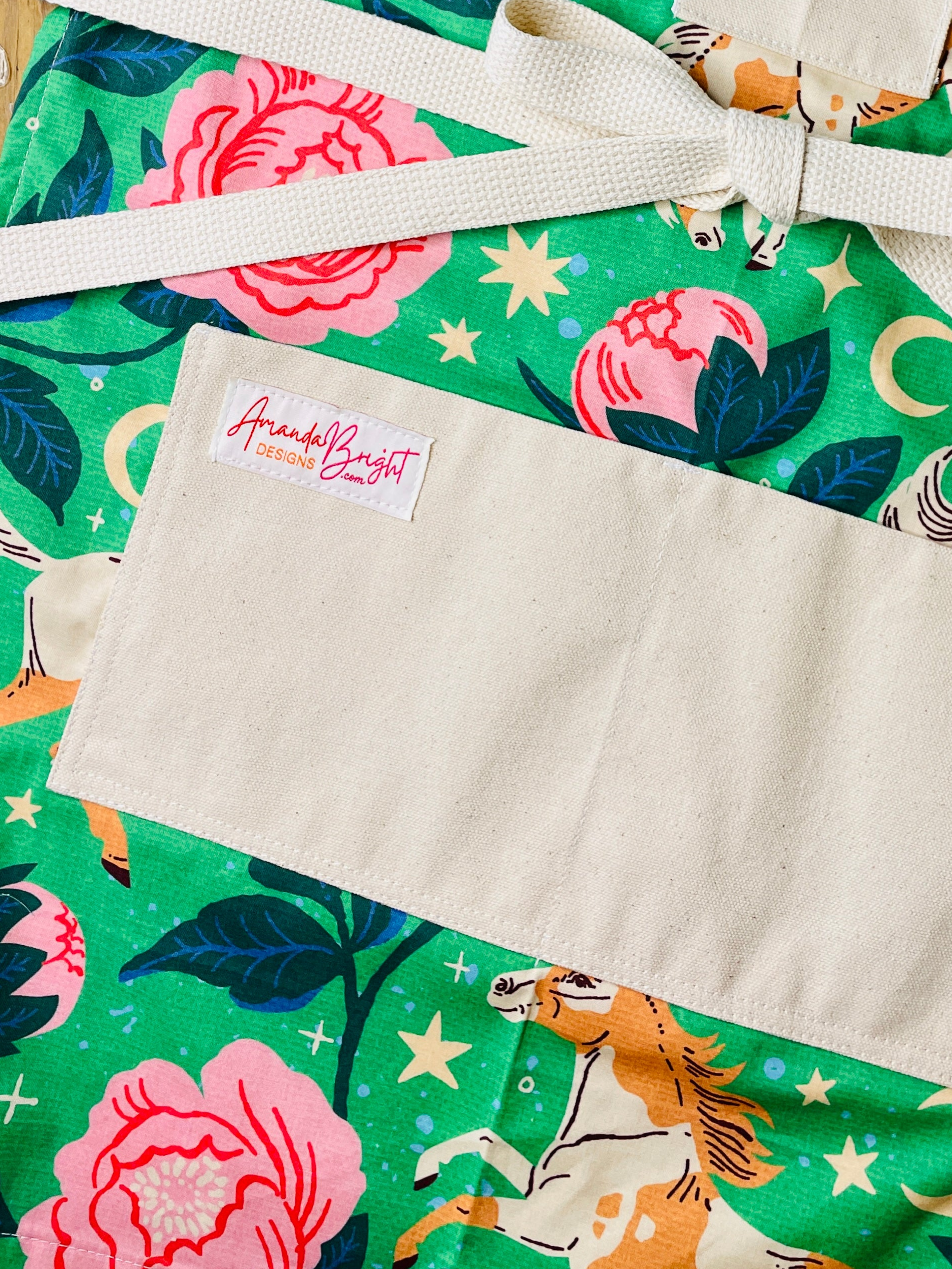 moonlit meadows pockets apron Galloping pintos, blooming peonies, and celestial moons and stars come together on a vibrant emerald green background 