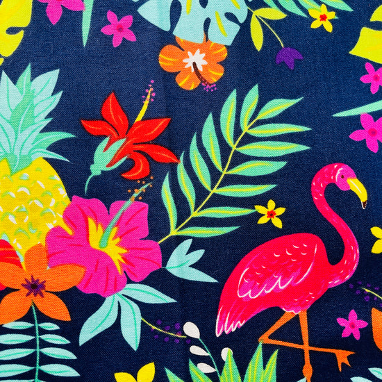 Amanda Bright Designs Nikki multicolored tropical Florida Hawaii floral apron with pink flamingo patterns on a blue background, featuring cotton strings and canvas pockets