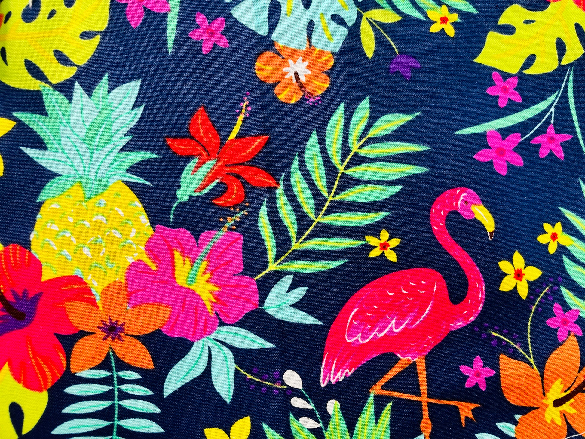 Amanda Bright Designs Nikki multicolored tropical Florida Hawaii floral apron with pink flamingo patterns on a blue background, featuring cotton strings and canvas pockets