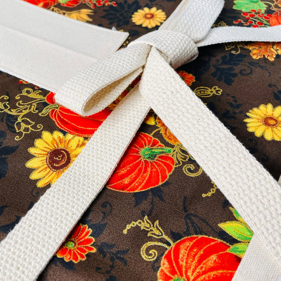 Amanda Bright Deisgns Nina Apron shows strings and Fabric with autumnal design featuring pumpkins and leaves