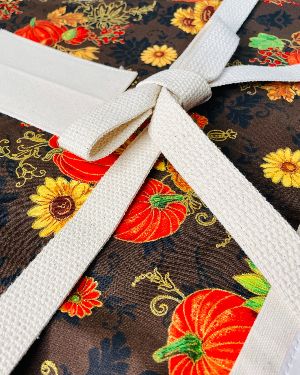 Amanda Bright Deisgns Nina Apron shows strings and Fabric with autumnal design featuring pumpkins and leaves