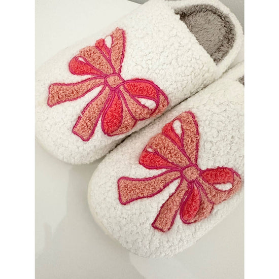 White slippers with pink bows on a light background