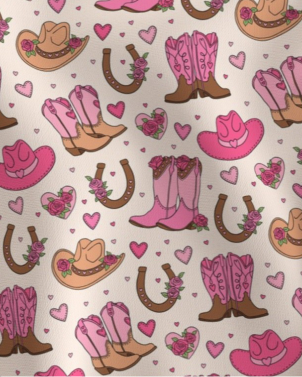 Pattern of pink and brown cowboy boots, pink cowboy hats, roses, hearts and horseshoes Amanda Bright Designs couture apron collection