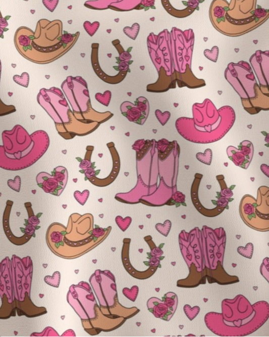 Pattern of pink and brown cowboy boots, pink cowboy hats, roses, hearts and horseshoes Amanda Bright Designs couture apron collection