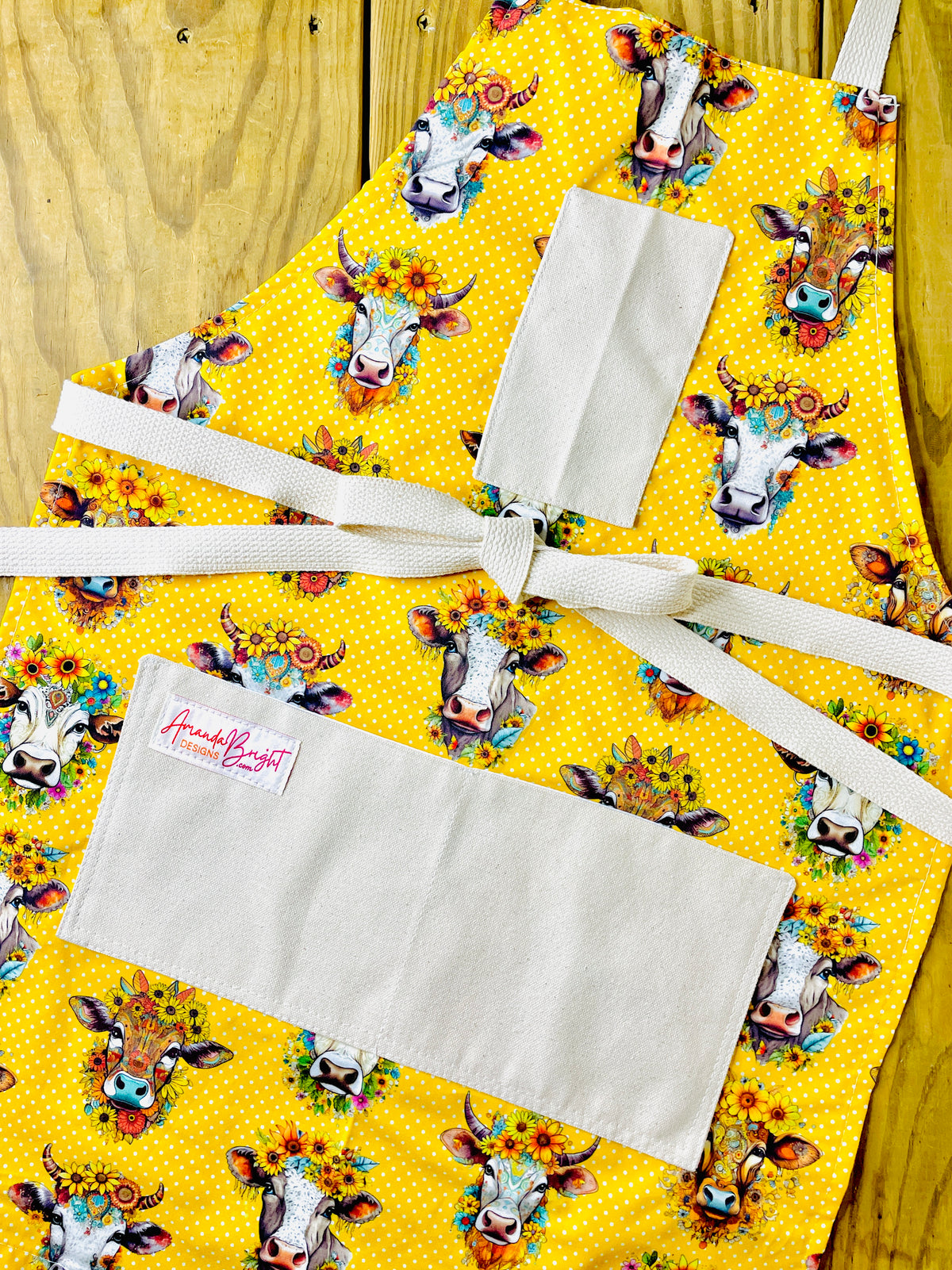 Amanda Bright Designs hand drawn cows heads with sunflowers and daisies on golden yellow polkadot background couture designer apron