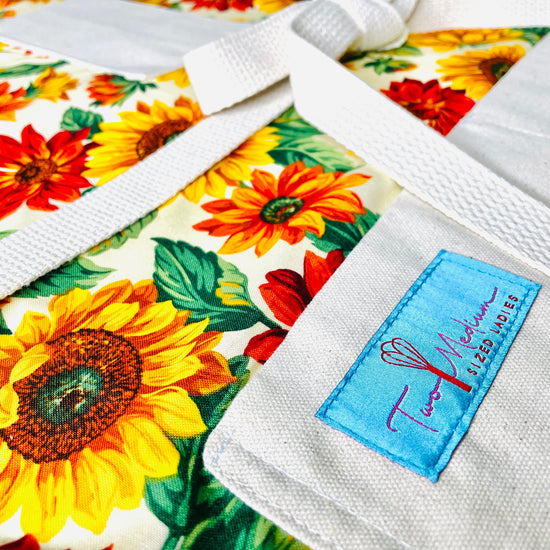 Two Medium Sized Ladies Teresa Apron Sunflowers Pattern Burnt Sienna Pumpkin Orange Goldenrod Close up view