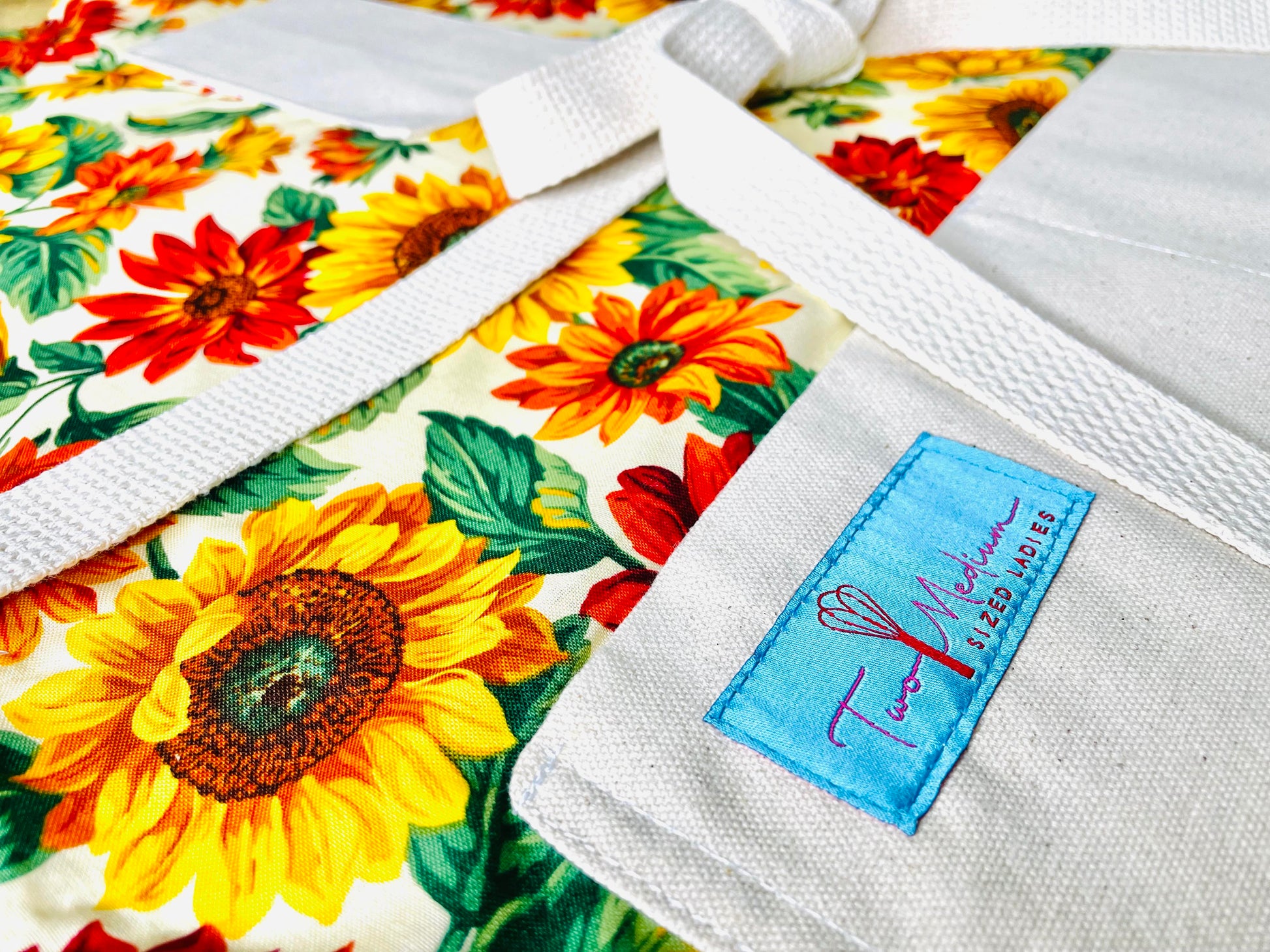 Two Medium Sized Ladies Teresa Apron Sunflowers Pattern Burnt Sienna Pumpkin Orange Goldenrod Close up view