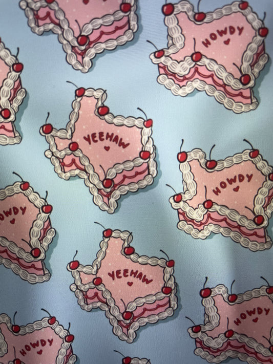 Pink Texas Shaped Iced Cakes with frosting and cherries on a light blue backgroun Amanda Bright Designs Couture Apron Collection