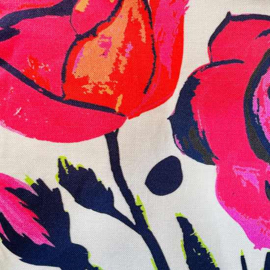Amanda Bright Designs apron pattern Close-up of a fabric with colorful floral pattern featuring pink, red, and black roses on a white background