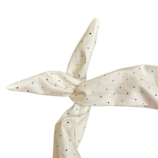 Amanda Bright Designs ivory fabric headband with small multicolored polka dots, tied in a knot 