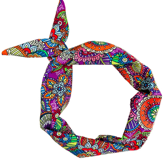 A knotted fabric headband with a vibrant, multicolored paisley and floral pattern by Amanda Bright Designs