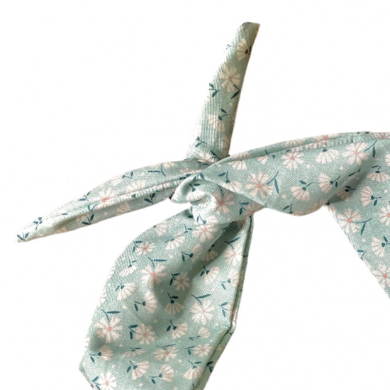 Amanda Bright Designs cotton moldable headband with a soft green base, featuring a delicate white and yellow floral pattern with small green leaves, tied in a knot on a solid white background.