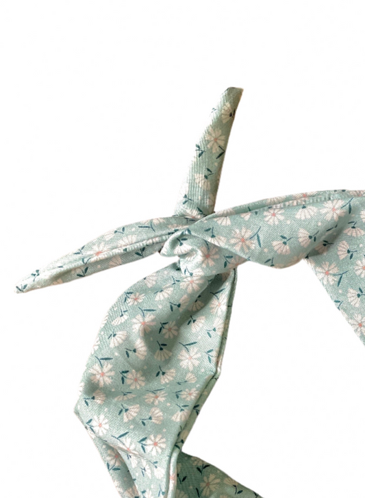 Amanda Bright Designs cotton moldable headband with a soft green base, featuring a delicate white and yellow floral pattern with small green leaves, tied in a knot on a solid white background.