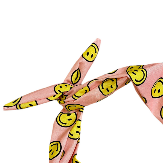 Pink headband with a yellow smiley face pattern, tied in a knot