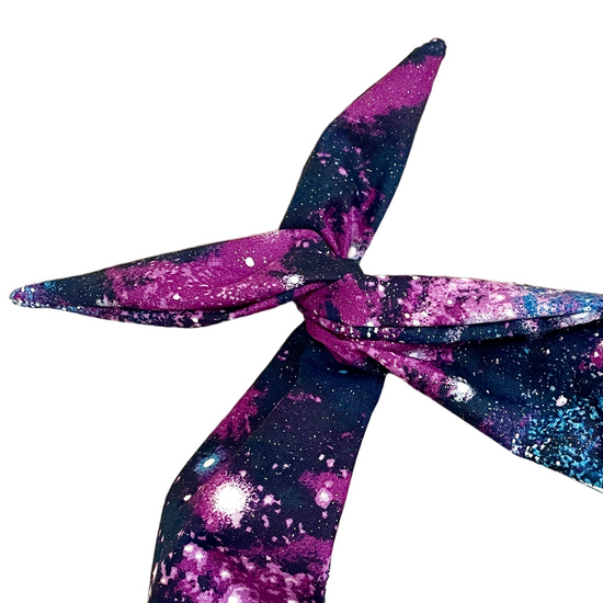 Amanda Bright Designs original tie headband space cosmos glitter headband for women in violet, magenta, midnight blue, and electric blue scattered with shimmering stars and celestial bursts, creating the look of a spectacular night sky and galaxy print